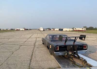 A car parked on a runway with a trailer attached, ready for transportation.