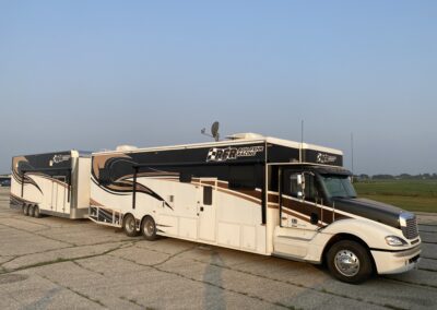 RV parked in lot with tropical palm trees.