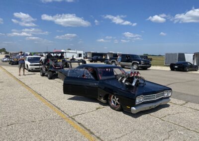 A black car with a powerful engine parked on the side of the road.