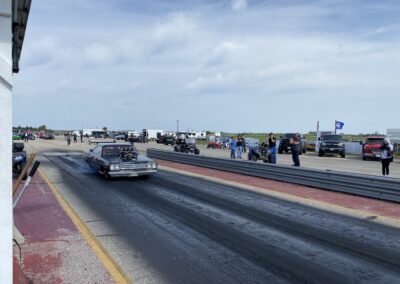 A car racing down a drag strip with a crowd of spectators watching the thrilling event.